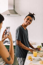 Junges Paar, das zu Hause Inhalte für ihren Kochblog aufnimmt. Junge Frau, die ihren Freund beim Kochen in der Küche aufnimmt. Food-Blogger beim Online-Streaming. - JLPSF03290