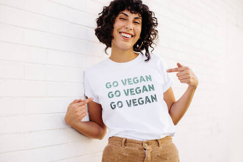 Glückliche vegane Aktivistin, die in die Kamera lächelt und ein T-Shirt mit der Aufschrift 