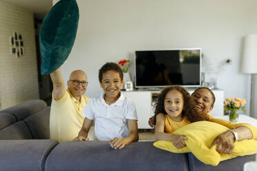 Smiling girl and boy with parents on sofa at home - VIVF00002