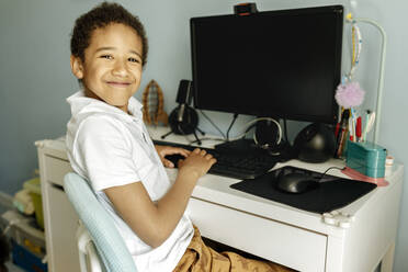 Smiling boy in front of desktop PC at home - VIVF00012