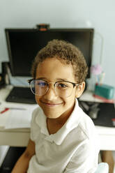 Lächelnder Junge mit Brille vor einem Desktop-PC zu Hause - VIVF00017