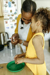 Glückliche Frau mit Tochter bei der Essenszubereitung in der Küche - VIVF00058