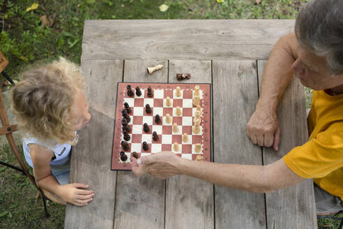 Grandfather and granddaughter playing chess on table - SVKF00592