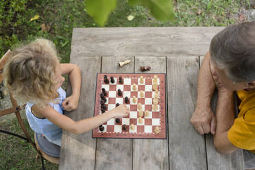 Enkelin und Großvater spielen Schachbrett im Garten - SVKF00593