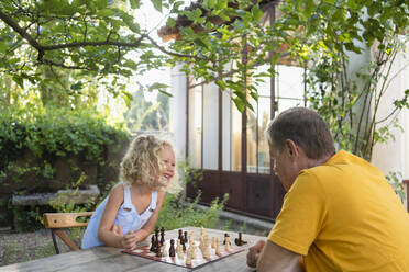 Granddaughter and grandfather playing chess in garden - SVKF00601