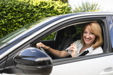 Happy mature woman sitting in car - SVKF00612