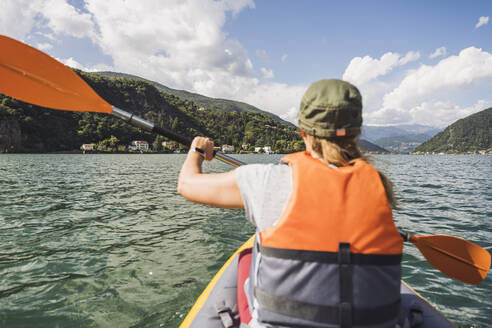 Frau mit Schwimmweste beim Kajakfahren auf dem See - UUF27488