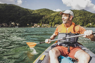 Glücklicher Mann hat Spaß beim Kajakfahren auf dem See an einem sonnigen Tag - UUF27491