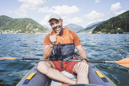 Happy mature man gesturing in kayak on lake - UUF27508