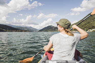 Ältere Frau beim Kajakfahren auf dem See an einem sonnigen Tag - UUF27512