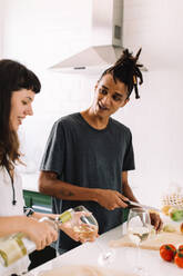 Glückliches junges Paar in der Küche. Ausschnitt eines liebevollen jungen Paares, das sich fröhlich unterhält, während es zu Hause in der Küche Essen zubereitet. Paar beim gemeinsamen Kochen. - JLPSF03446