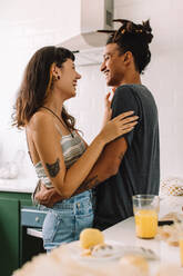 Cropped shot of a happy young couple standing together indoors. Romantic young couple smiling affectionately while embracing each other in the kitchen at home. - JLPSF03455