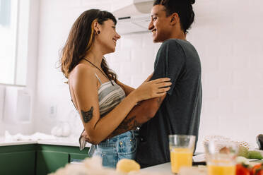 Sweet couple sharing a romantic moment in the kitchen. Cropped shot of a young couple smiling at each other affectionately while standing together in their kitchen at home. - JLPSF03456
