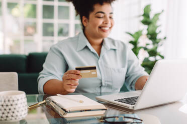 Woman at home doing online shopping with credit card and laptop. Female making online payment using credit card for shopping on ecommerce website. - JLPSF03546