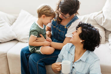 LGBT-Paar mit Sohn zu Hause: Liebevolles lesbisches Paar, das mit seinem Sohn spielt, während es zu Hause Zeit miteinander verbringt. - JLPSF03587