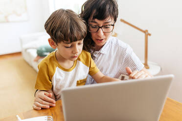 Mutter bringt ihrem Sohn bei, wie man zu Hause mit dem Laptop umgeht. Junge lernt Laptop mit Mutter. - JLPSF03602