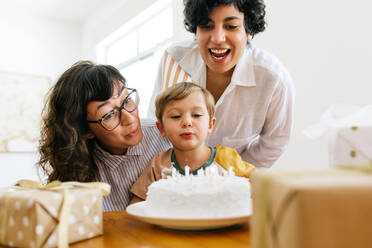 Junge Familie zusammen bläst Geburtstagskuchen Kerzen zu Hause. Mütter feiern den Geburtstag ihres Sohnes. - JLPSF03623