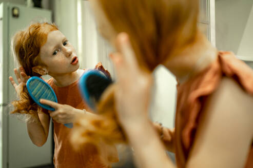 Mädchen beim Bürsten der Haare vor dem Spiegel - ANAF00106