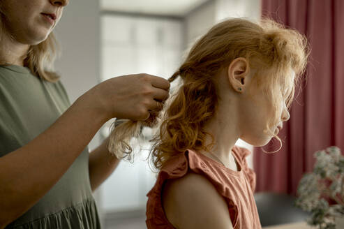 Mutter flechtet die Haare ihrer Tochter zu Hause - ANAF00124