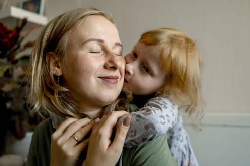 Tochter umarmt Mutter von hinten und küsst sie zu Hause auf die Wange - ANAF00131