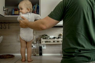 Ein kleines Mädchen steht mit seinem Vater zu Hause auf dem Küchentisch - ANAF00136