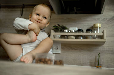 Süßes kleines Mädchen sitzt auf der Küchentheke zu Hause - ANAF00137