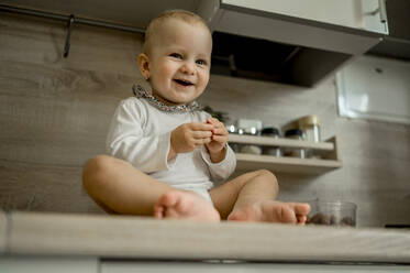 Glücklich niedlichen Baby-Mädchen sitzt auf Küchenzeile zu Hause - ANAF00138