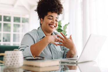 Businesswoman sitting at table and video calling on laptop. Woman video conferencing while working from home. - JLPSF03835