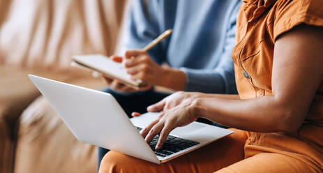 Unbekannte Geschäftsfrauen, die einen Laptop benutzen, während sie in einer Bürolobby eine Diskussion führen. Zwei Unternehmerinnen bei einer Besprechung in einem modernen Büro. - JLPSF03964