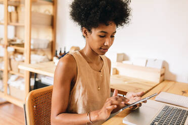 Female jewelry designer checking orders on phone in workshop. Business owner working on phone in jewelry designing studio. - JLPSF04109