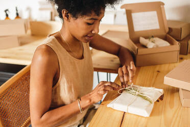 E-Commerce-Unternehmerin in einem Schmuckatelier, die handgefertigte Schmuckpakete dekoriert. Handwerker in einer Werkstatt, der Dekorationen auf Schmuckpakete für den Verkauf legt. - JLPSF04141