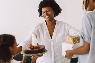 Familie feiert Geburtstag zu Hause: Mädchen überraschen ihre Mutter mit Geburtstagskuchen und Geschenken. - JLPSF04352