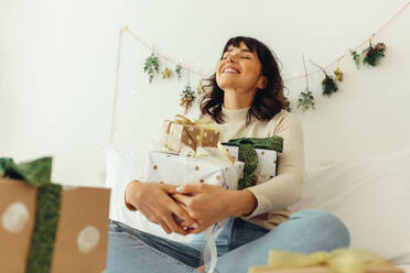 Close up von lächelnden Frau zu Hause sitzen mit Weihnachtsgeschenke. Glückliche Frau genießt Weihnachten Zeit zu Hause. - JLPSF04481