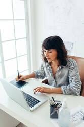 Architektin mit digitalem Schreibblock zum Zeichnen von Architekturentwürfen. Geschäftsfrau arbeitet im Büro am Laptop. - JLPSF04490