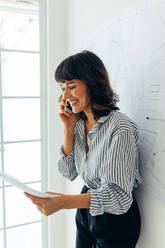 Woman entrepreneur discussing business with clients on mobile phone. Portrait of businesswoman working in office. - JLPSF04504