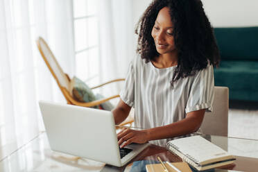 Young woman working on laptop at home. Female using laptop while sitting at table. - JLPSF04514