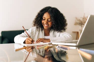 Happy girl doing homework. Girl completing her school work at home. - JLPSF04535