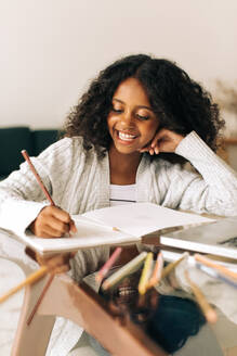 Mädchen sitzt zu Hause und studiert am Schreibtisch. Mädchen schreibt in ihrem Buch zu Hause. - JLPSF04536