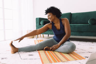 Afrikanische Frau beim Stretching zu Hause. Reife Frau zu Hause hält sich durch Sport fit. - JLPSF04549