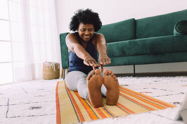 Reife junge Frau macht Yoga-Übungen zu Hause. Afrikanische Frau übt Yoga zu Hause auf der Matte. - JLPSF04551