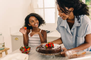 Nettes Mädchen hilft Mutter bei der Zubereitung von Kuchen zu Hause. Lächelndes Mädchen Kind mit Frau macht Kuchen in der Küche. - JLPSF04611