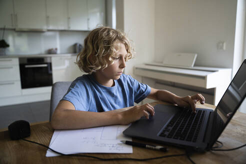 Boy doing homeschooling through laptop on table at home - NJAF00024