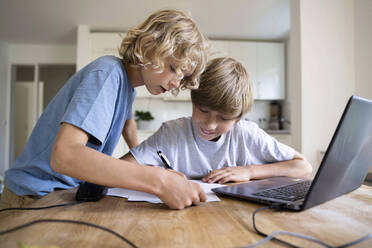 Junge hilft seinem Bruder bei den Hausaufgaben zu Hause - NJAF00027