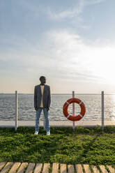 Businessman standing by lifeguard ring on footpath - VPIF07497