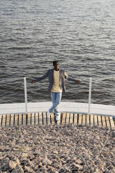 Smiling businessman in front of railing on promenade - VPIF07505