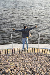 Businessman with arms outstretched in front of railing on promenade - VPIF07506