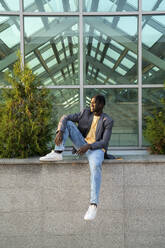 Contemplative young businessman in front of glass house - VPIF07530