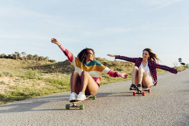 Beautiful skaters practicing riding skate board on street in a sunny day - ADSF39347