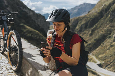 Cyclist wearing helmet using smart phone by bicycle - DMGF00868