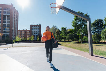 Junge Sportlerin mit Basketball auf einem Sportplatz - MEUF08170